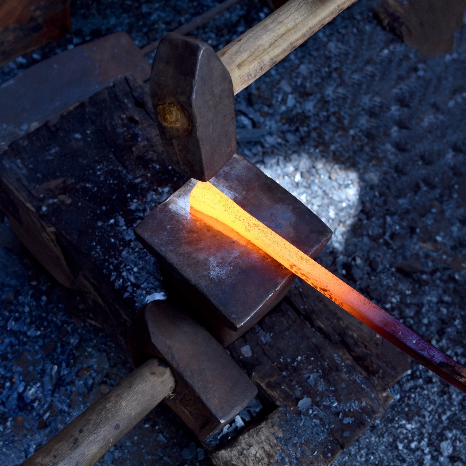 Image of a hot iron nail being hand forged on an anvil